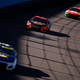A photo of four Nascar racers driving round an oval track.